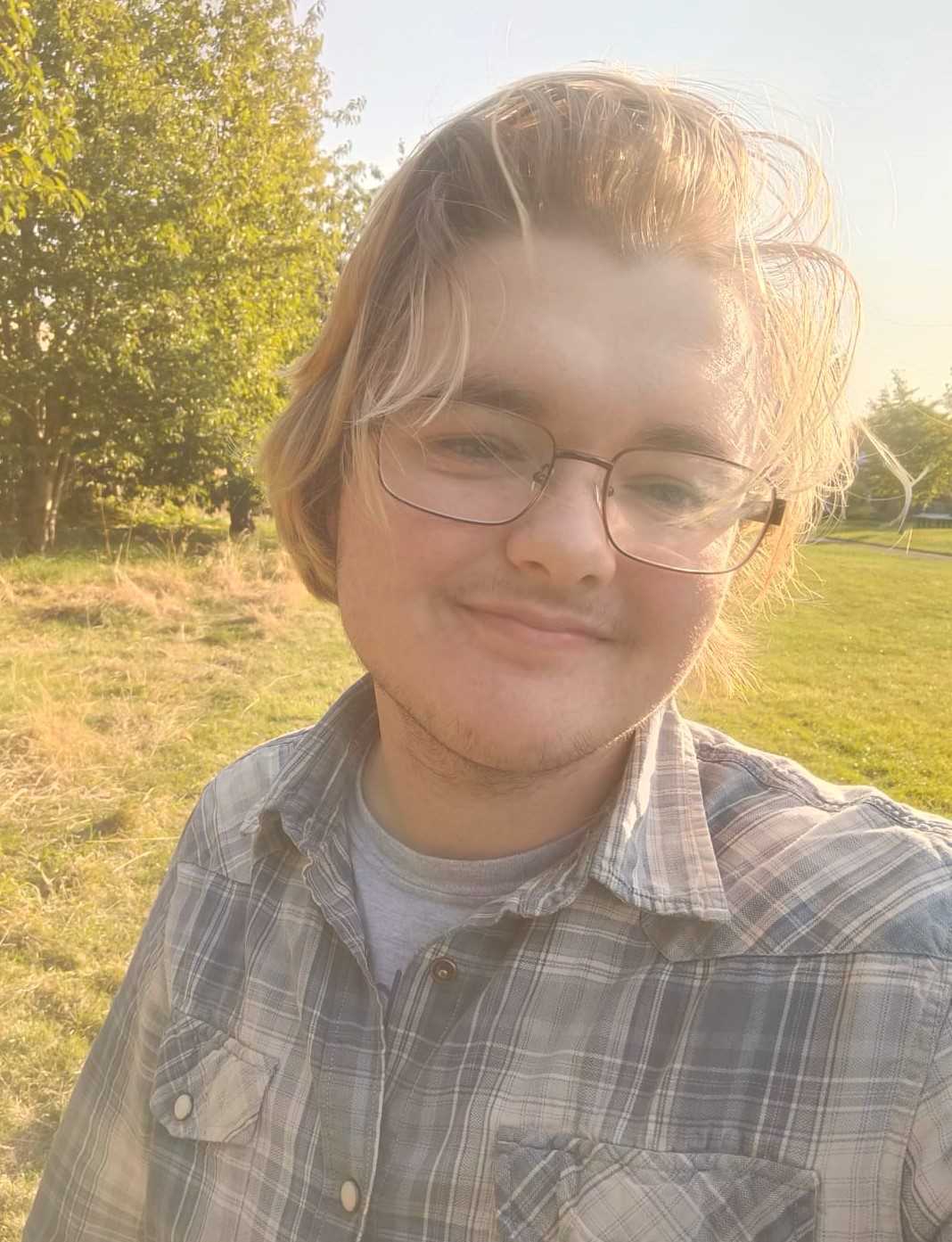 Selfie of Yeva, a smiling white guy with glasses in a sunny grassland.