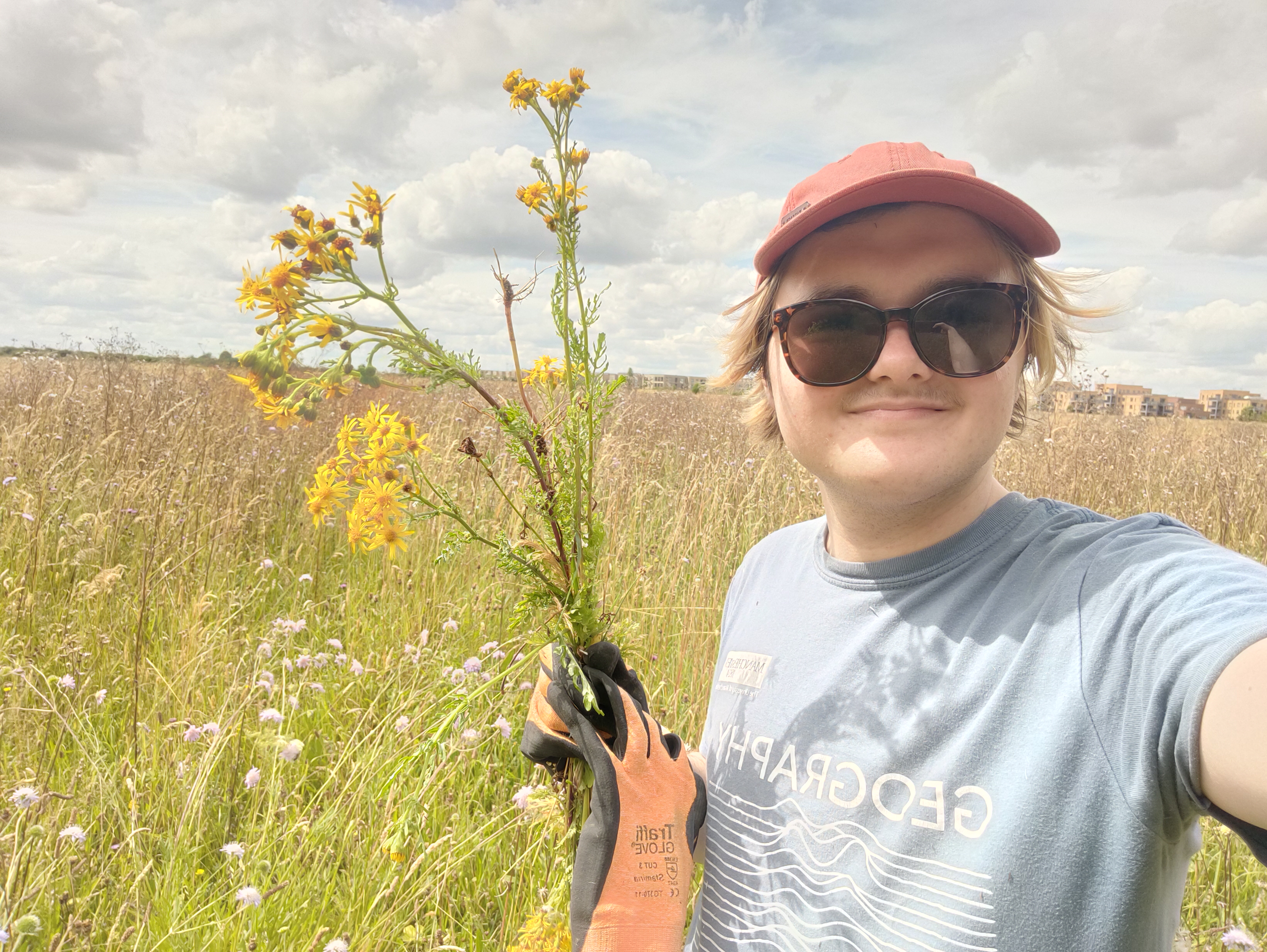 Selfie of Yeva holding up some ragwort on a sunny day.